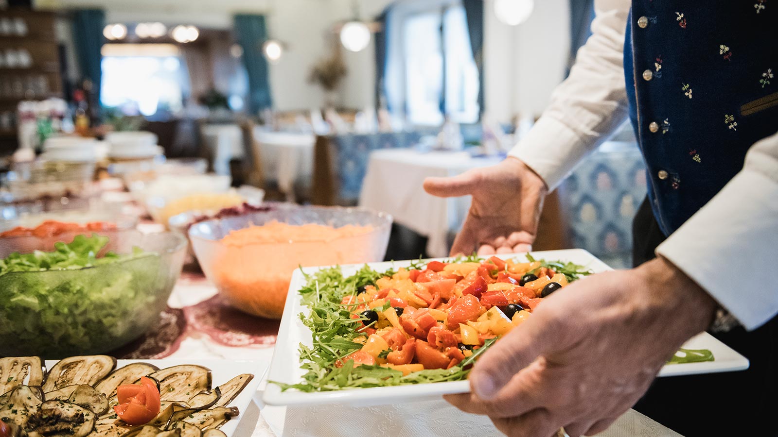 Detail eines Kellners, der ein Gericht auf den Buffet-Tisch im Restaurant am Passo Campolongo stellt.